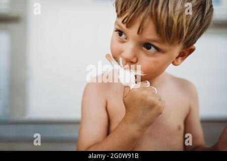 Un jeune garçon mignon qui mange de la glace en regardant sur le côté extérieur en été Banque D'Images