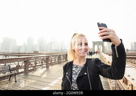 Bonne femme prenant le selfie sur le passage piéton à megapolis Banque D'Images