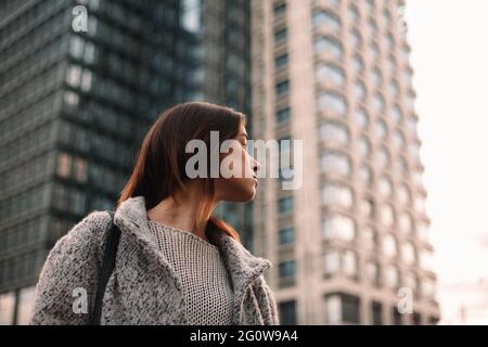 Femme réfléchie non binaire debout dans la rue en ville Banque D'Images