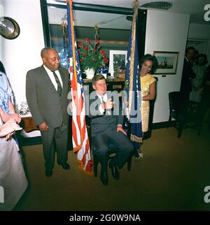 KN-C28776 29 mai 1963 le Président John F. Kennedy assiste à un anniversaire surprise tenu en son honneur par des membres du personnel de la Maison Blanche. Le valet du président Kennedy, George E. Thomas, est à gauche ; une femme non identifiée se trouve à droite. Visible sur la porte tout à droite : Ron Pontius, agent du service secret de la Maison Blanche, Evelyn Lincoln, secrétaire personnel du président Kennedy. Navy Mess Hall, White House, Washington, D.C. Veuillez indiquer « Cecil Stoughton. Photos de la Maison Blanche. John F. Kennedy Library and Museum, Boston Banque D'Images