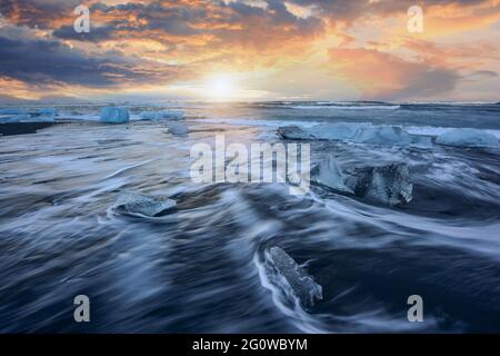 Magnifique coucher de soleil sur la célèbre plage de Diamond, floe de glace sur sable noir Banque D'Images