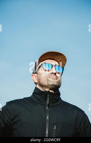 Homme avec des lunettes de soleil et un chapeau par temps ensoleillé Banque D'Images
