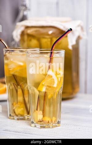 Boisson faite maison au kombucha fermentée avec citron et gingembre. Verres de limonade d'été sur table en bois Banque D'Images