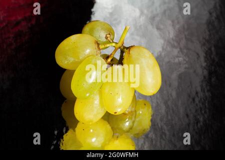 raisin blanc sur fond réfléchissant noir Banque D'Images