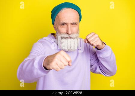 Photo portrait d'un homme âgé combattant portant un sweat-shirt violet isolé sur fond jaune vif Banque D'Images