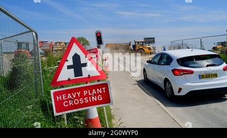 voiture en attente au passage à niveau d'une usine lourde lors de la construction de la nouvelle route orbitale est de leeds yorkshire royaume-uni Banque D'Images