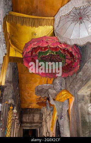 Cambodge. Partie du complexe du temple d'Angkor Wat. Couloir à l'intérieur du temple avec statues de moine. Décoration élaborée avec des tissus dorés et des parasols Banque D'Images