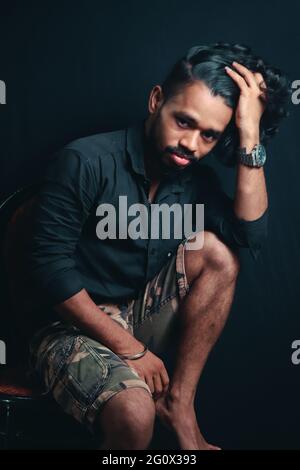 Jeune Indien beau homme hipster posant sur fond noir Banque D'Images