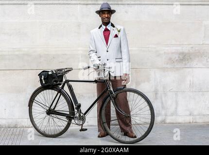 homme vêtu d'un costume debout à côté d'un vélo Banque D'Images