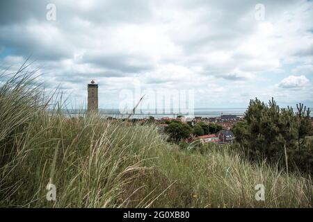 Phare au milieu d'un village tiré du sommet d'une colline par une journée nuageux Banque D'Images