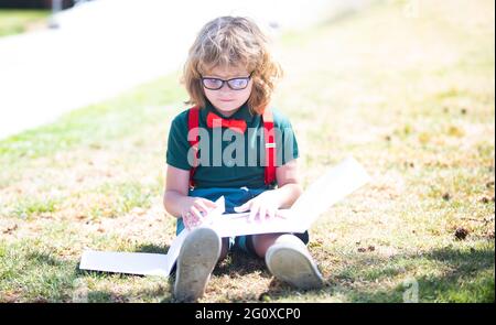 intelligent curieux nerd dans les verres lecture livre étude avec copybook extérieur, de retour à l'école Banque D'Images