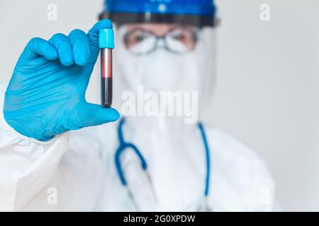 Femme médecin ou infirmière en costume de protection tenant un blo positif Banque D'Images