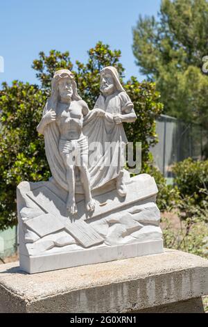 Santa Inez, CA, Etats-Unis - 3 avril 2009: San Lorenzo Seminary. Gare de la Croix numéro 10 statue en marbre blanc. Jésus dépouillé de vêtements. Folia verte Banque D'Images