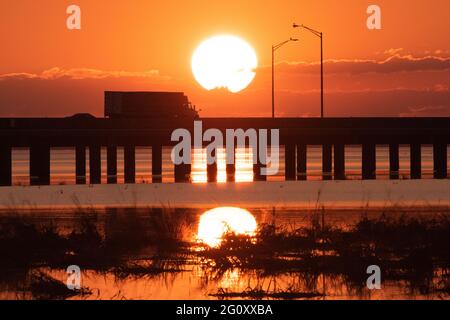 Un semi-tracteur-remorque traverse Mobile Bay en Alabama au coucher du soleil le 26 octobre 2020. Banque D'Images