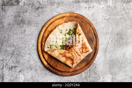 Sandwich shawarma avec ingrédients sur une planche à découper ronde en bois sur fond gris foncé. Vue de dessus, plan d'appartement Banque D'Images
