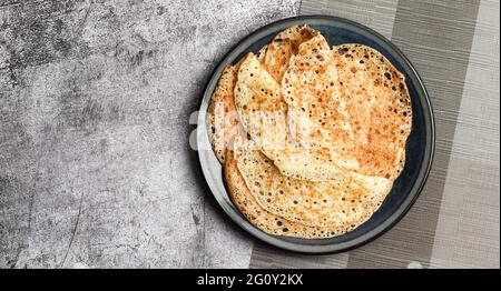 Crêpes russes traditionnelles fines sur une plaque ronde sur un fond gris foncé. Vue de dessus, plan d'appartement Banque D'Images