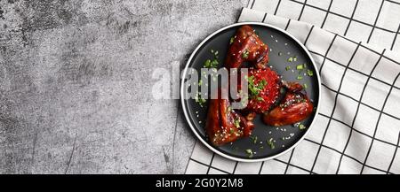 Ailes de poulet rôties avec risotto aux betteraves sur une assiette ronde sur fond gris foncé. Vue de dessus, plan d'appartement Banque D'Images