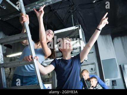 Femme avec un fils adolescent pointant vers quelque chose dans la salle de quête Banque D'Images