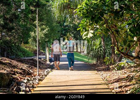 MacKay, Queensland, Australie - juin 2021 : couple marchant dans les jardins botaniques avec leur jeune enfant sur les épaules de la mère Banque D'Images