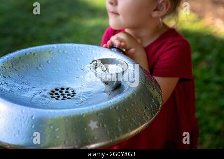 MacKay, Queensland, Australie - juin 2021 : une jeune fille presse la fontaine d'eau dans un parc pour boire un verre Banque D'Images