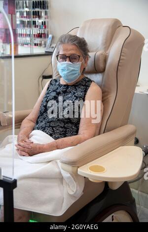 Une femme hispanique de 84 ans se fait offrir un ensemble pédicure/manucure dans son salon de beauté local. Banque D'Images