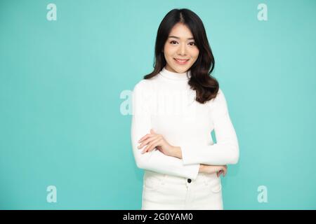 Portrait des femmes asiatiques avec les bras croisés et le sourire isolé sur fond vert Banque D'Images