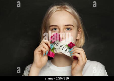 Jeune fille attrayante avec patch et fleurs rouges sur sa bouche sur fond noir Banque D'Images