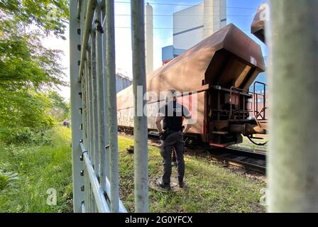 Wolfsburg, Allemagne. 04e juin 2021. Un policier se trouve à côté d'un train à charbon sur le terrain de la centrale à charbon VW (photographiée à travers une clôture). Les manifestants du groupe d'action « Get Off the Gas » occupent la centrale au charbon de l'usine Volkswagen de Wolfsburg depuis le début de la matinée. Credit: Julian Stratenschulte/dpa/Alay Live News Banque D'Images