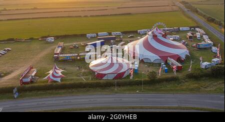 Un fermier a tendance à son champ dans un tracteur tandis qu'un cirque s'installe à côté du Blue Dolphin Holiday Park et du Plow Pub Aerial Images Drone Air Filey Banque D'Images