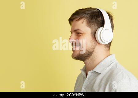 Vue latérale du jeune homme du Caucase isolé sur fond jaune clair. Concept des expressions faciales, des émotions humaines. Banque D'Images