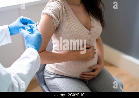 Médecin effectuant l'injection du vaccin Covid-19 à la femme enceinte patient Banque D'Images