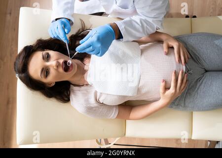 Dentiste traitant les dents de la jeune femme enceinte patient couché Clinique Banque D'Images