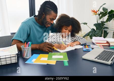 Le père aide sa fille à faire ses devoirs à l'école à la maison. Fête des pères, papa et écolière heureux, famille heureuse Banque D'Images