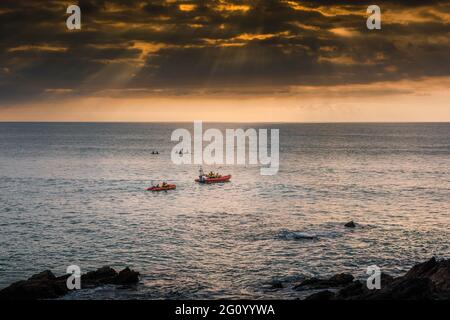 Les deux bateaux de sauvetage côtiers RNLI de Newquay sur une légende d'urgence alors que le soleil se couche sur la baie de Fistral, dans les Cornouailles. Banque D'Images