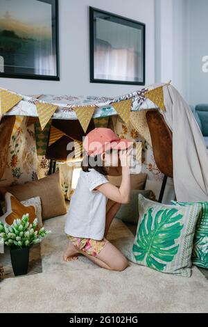 Petite fille jouant avec des jumelles en carton tout en campant à la maison dans le salon Banque D'Images