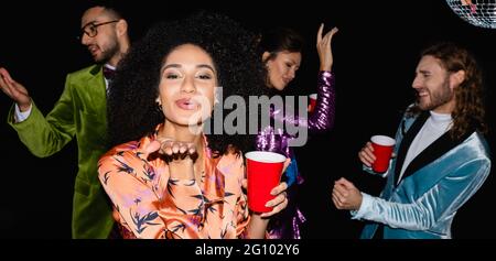 positive african american femme avec le geste de baiser soufflant sur la partie avec des amis multiraciaux, bannière Banque D'Images