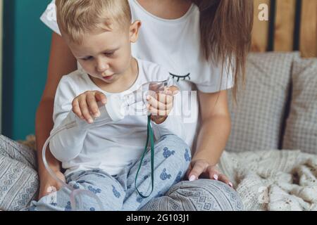 Femme avec son enfant qui fait inhalation avec nébuliseur à la maison Banque D'Images