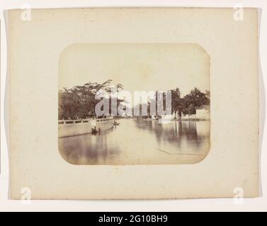 Le Mas Kali. Le Mas Kali à Surabaya avec un haut mur et des arbres sur la gauche, au milieu au loin une maison et aussi une maison. Une seule prauw amarrée au loin. Partie de l'album photo des fabricants Surabayasche Vereeniging van Sugar offert à Frederik Beyerinck, résident de Surabaya. Banque D'Images