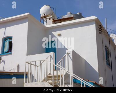 Vue rapprochée d'un bâtiment de style grec traditionnel dans les couleurs blanc et bleu avec la chaudière solaire à eau chaude sur le toit à Ayia Napa, Chypre. Banque D'Images