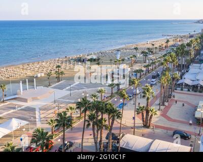 Vue aérienne supérieure donnant sur la promenade des palmiers de Finikoudes, route avec voitures, et plage centrale près de la mer Méditerranée dans la ville de Larnaca, Chypre. Banque D'Images
