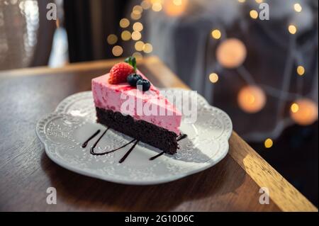 Gâteau au chocolat noir en tranches de fraise avec baies dans un plat blanc sur une table en bois Banque D'Images