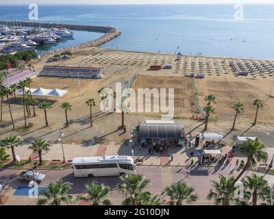 Vue aérienne supérieure donnant sur l'arrêt de bus central avec les personnes qui attendent à la promenade des palmiers de Finikoudes, la mer méditerranée, les yachts dans le port et la plage. Banque D'Images