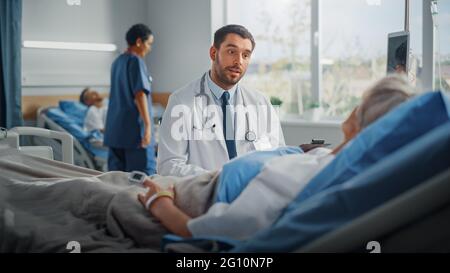 Service hospitalier : un médecin amical parle à une belle patiente sénior au lit, explique les résultats des tests, donne des conseils de rétablissement. Le médecin parle Banque D'Images