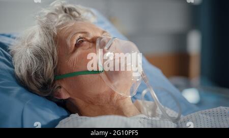 Hôpital: Portrait d'une belle femme âgée portant un masque d'oxygène dormant dans le lit, se rétablissant complètement après la maladie. La vieille dame rêve d'elle Banque D'Images
