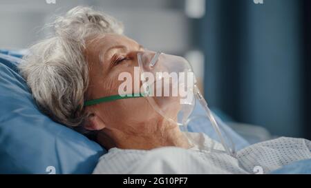 Hôpital: Portrait d'une belle femme âgée portant un masque d'oxygène dormant dans le lit, se rétablissant complètement après la maladie. La vieille dame rêve d'elle Banque D'Images