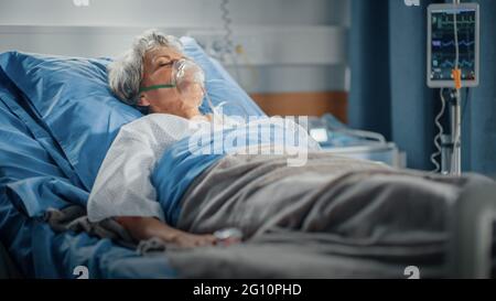 Hôpital: Portrait d'une belle femme âgée portant un masque d'oxygène dormant dans le lit, se rétablissant complètement après la maladie. La vieille dame rêve d'elle Banque D'Images