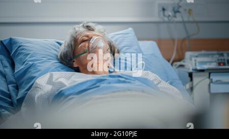 Hôpital: Portrait d'une belle femme âgée portant un masque d'oxygène dormant dans le lit, se rétablissant complètement après la maladie. La vieille dame rêve d'elle Banque D'Images