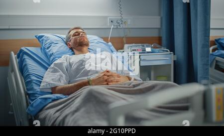 Hôpital: Portrait d'un jeune homme beau portant une canule nasale dormant dans le lit, se rétablissant complètement après la maladie. Un patient de sexe masculin rêvait de lui Banque D'Images