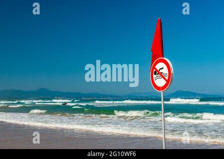 FRANCE. PYRÉNÉES-ATLANTIQUES (64), BIARRITZ, PANNEAU DE NATATION INTERDIT ET DRAPEAU ROUGE SUR LA PLAGE CA’TE DES BASQUES Banque D'Images