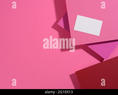 la carte de visite rectangulaire vierge se trouve sur un fond rose moderne de feuilles de papier avec une ombre. Modèle commercial, pose à plat Banque D'Images